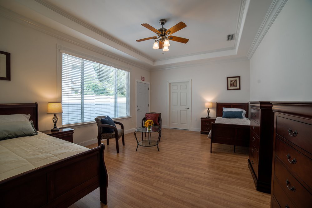 A spacious bedroom with two beds, armchairs, and a large window providing natural light.