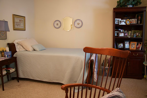 A cozy and well-decorated bedroom featuring a bed, rocking chair, and bookcase.