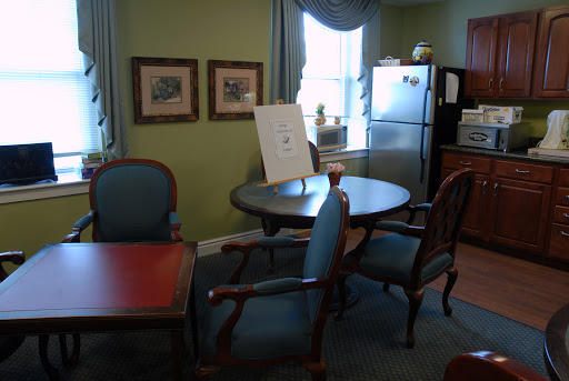 An inviting office space featuring a table with chairs, a refrigerator, and framed artwork on the walls.