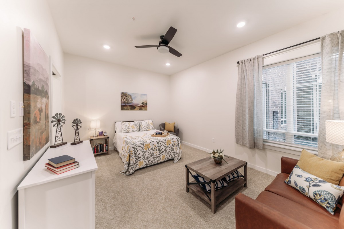 A modern and minimalist bedroom with a cozy bed, nightstand, and ceiling fan.