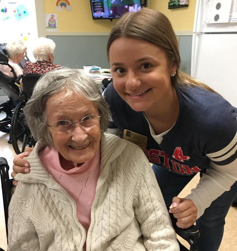 A joyful moment shared between a caregiver and an elderly resident in a nursing home.
