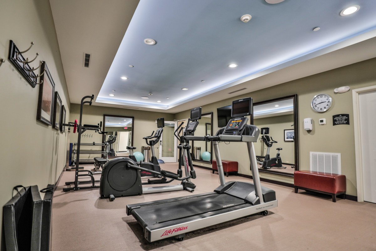 A modern gym with various exercise equipment including treadmills and elliptical machines.