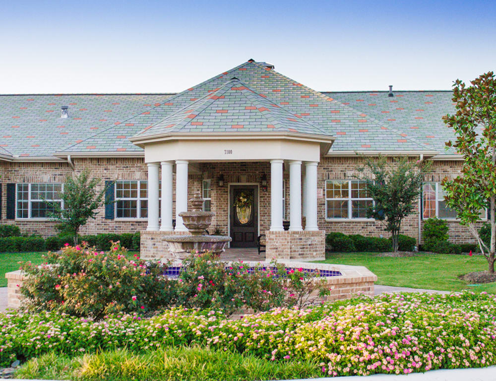 A beautiful house with a landscaped garden and columned entrance.