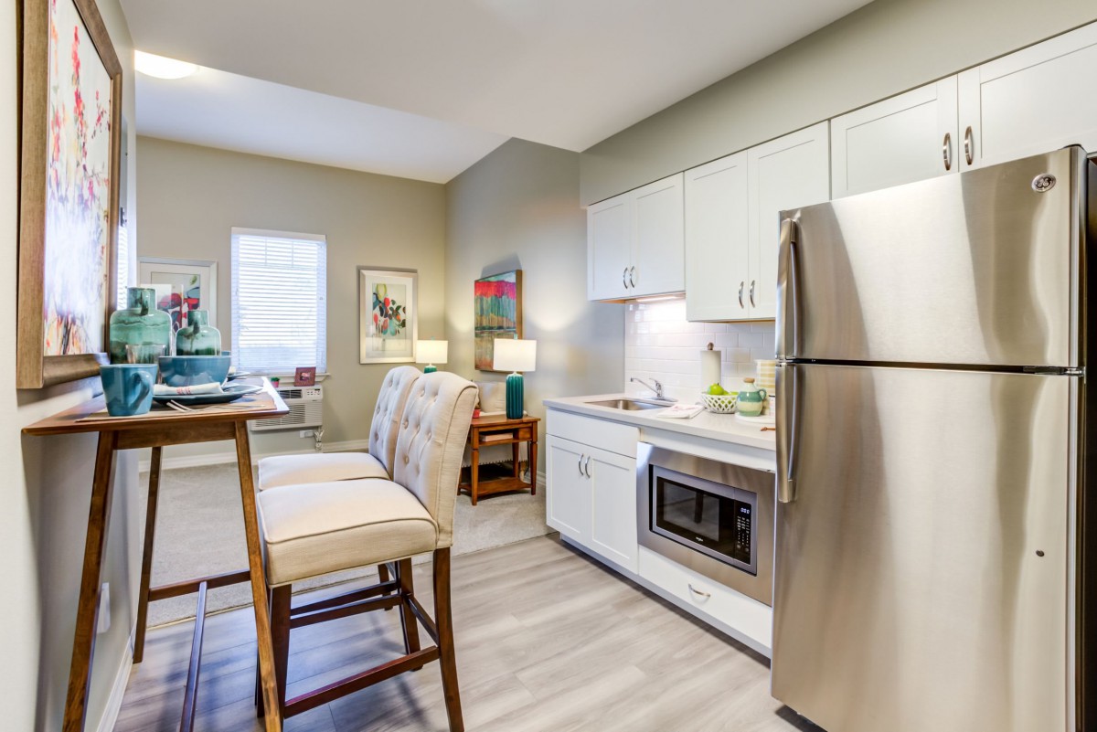 A modern kitchen in an apartment featuring stainless steel appliances and a small dining area.