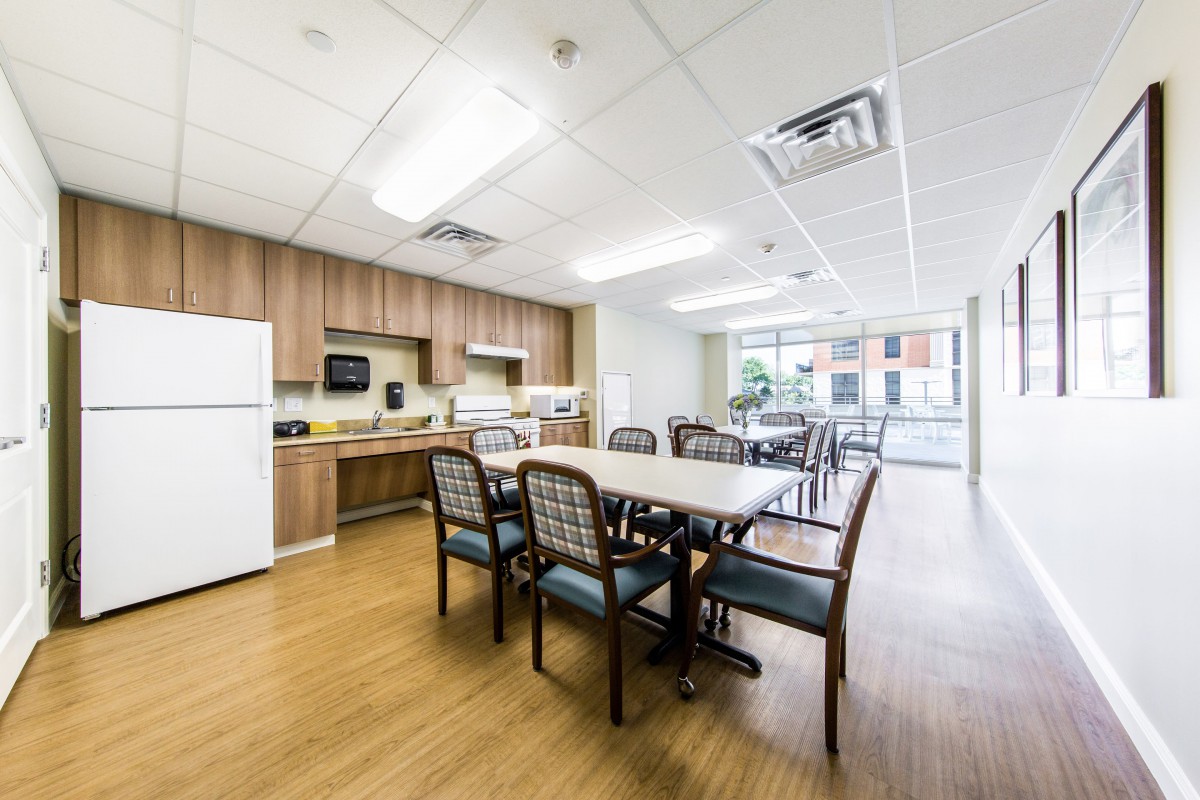 A modern kitchen and dining area with wooden cabinets, a refrigerator, and a table with chairs.