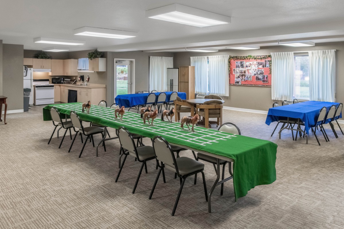 A community center room set up for an event with tables and chairs covered in green tablecloths.