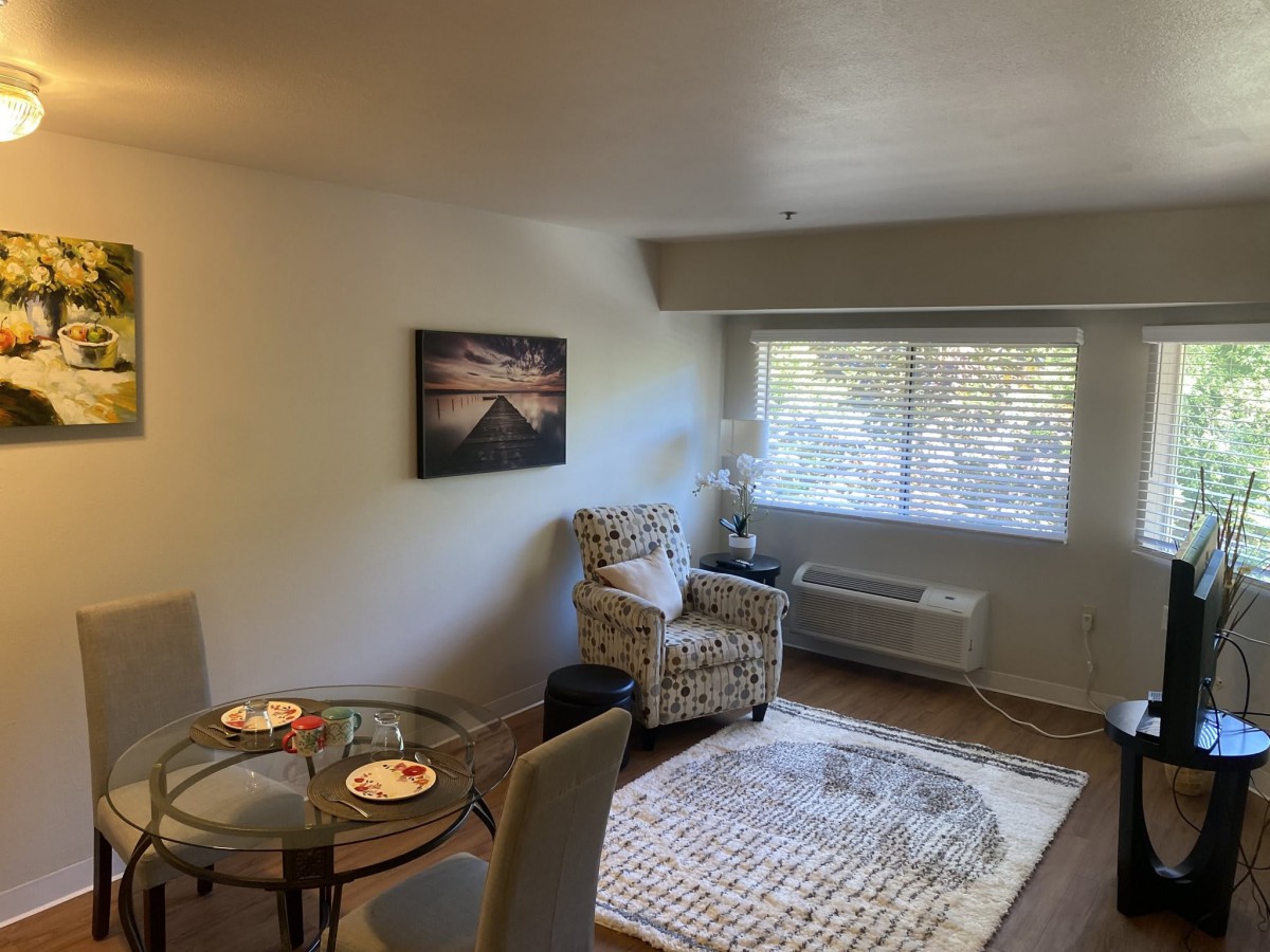 Cozy living room with an armchair, dining table, and wall art.