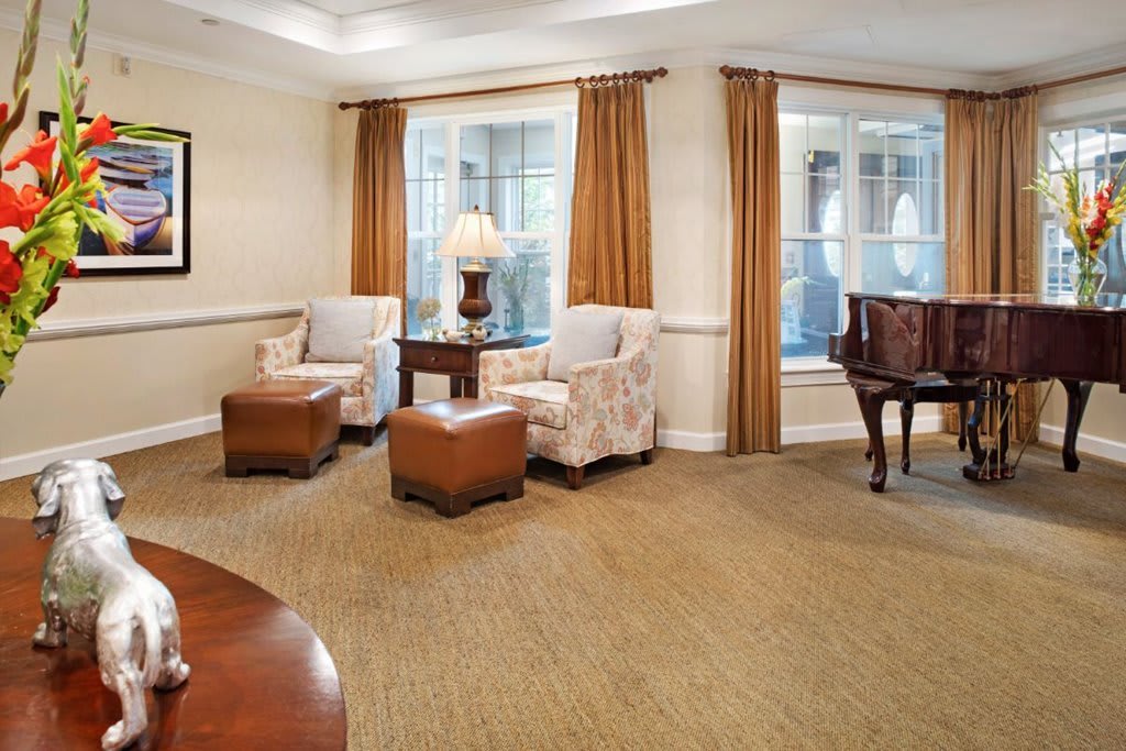 A cozy living room with armchairs, a small table, and large windows adorned with curtains.