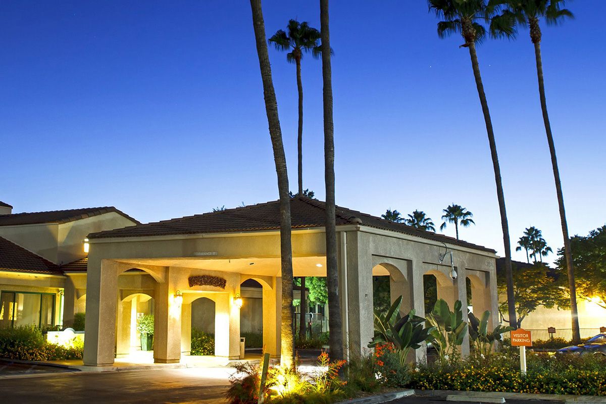 A hotel building with palm trees and evening lighting.