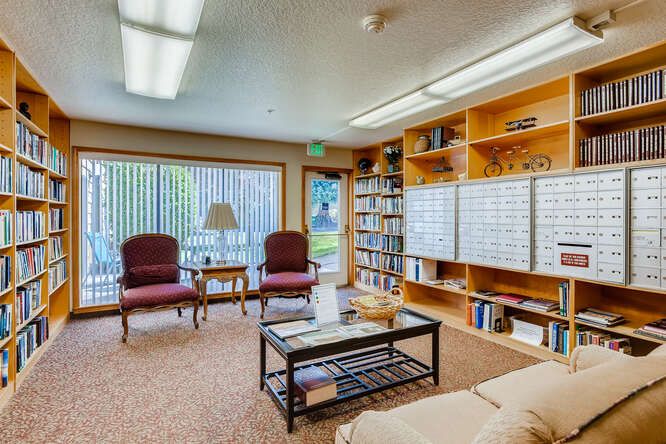 Cozy library room with bookshelves, chairs, and a glass table.