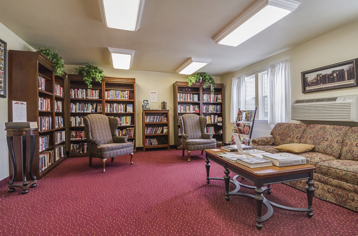 A cozy reading room with bookshelves, comfortable chairs, and ample natural light.