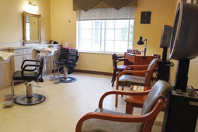 An interior view of a cozy barbershop with chairs, mirrors, and a waiting area.