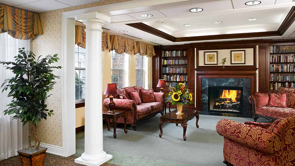 A traditional living room with elegant furnishings, featuring a cozy fireplace and built-in bookshelves.
