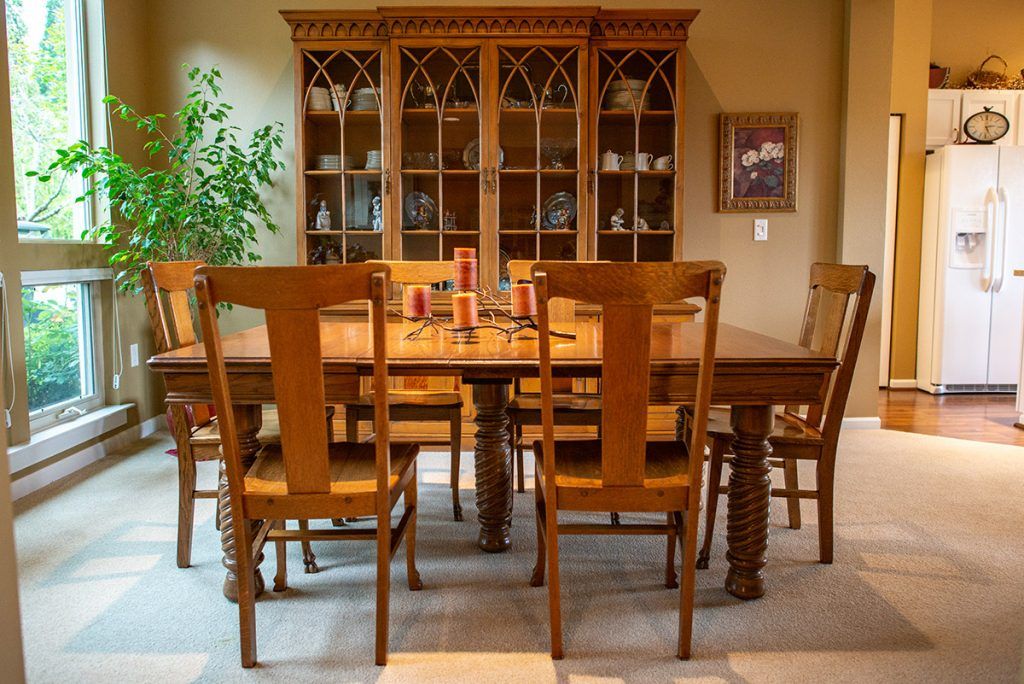 A cozy dining room featuring a wooden table, chairs, and a decorative cabinet.