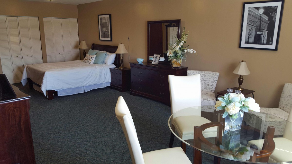 A well-furnished hotel room with a bed, table, and chairs.