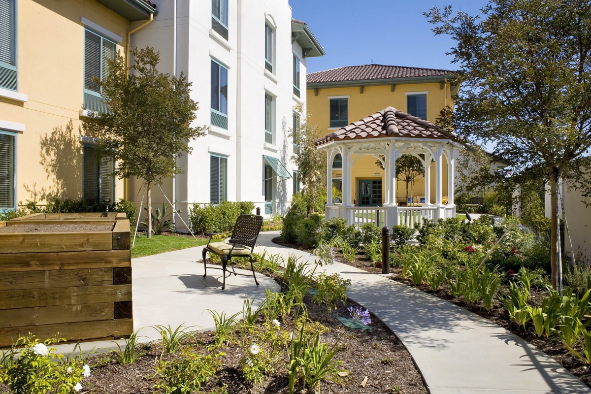 A well-maintained garden area with a gazebo and benches outside a residential building.