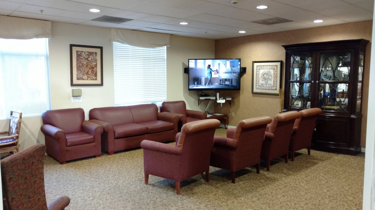 A comfortable waiting room with leather sofas and chairs arranged in front of a television.