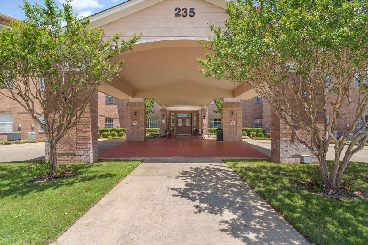 Covered entrance to a building with surrounding greenery.