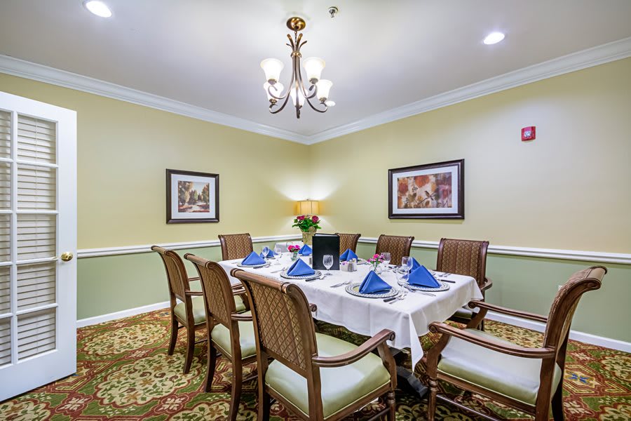 A well-decorated dining room with a table set for a meal, featuring blue napkins and elegant lighting.