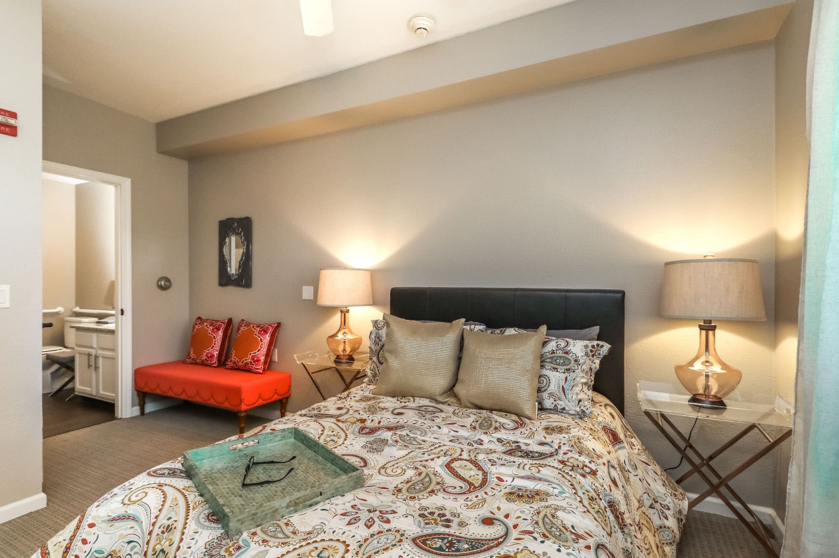 A modern and cozy bedroom with stylish decor, featuring a bed with patterned bedding and two lamps on bedside tables.