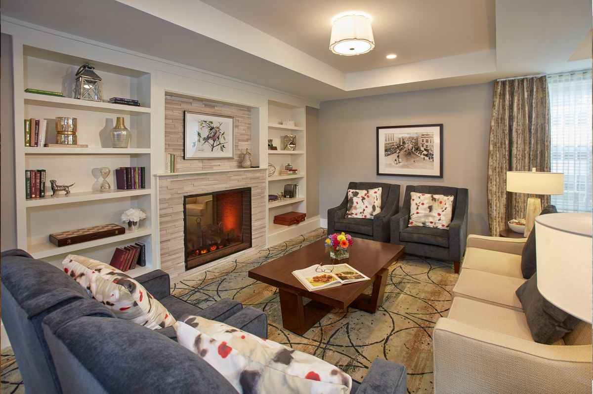 A cozy and modern living room featuring a fireplace, stylish sofas, and a wooden coffee table surrounded by built-in bookshelves.