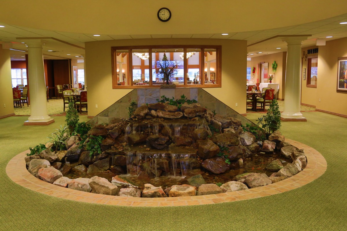 An indoor waterfall feature in a lobby setting with rocks and plants.