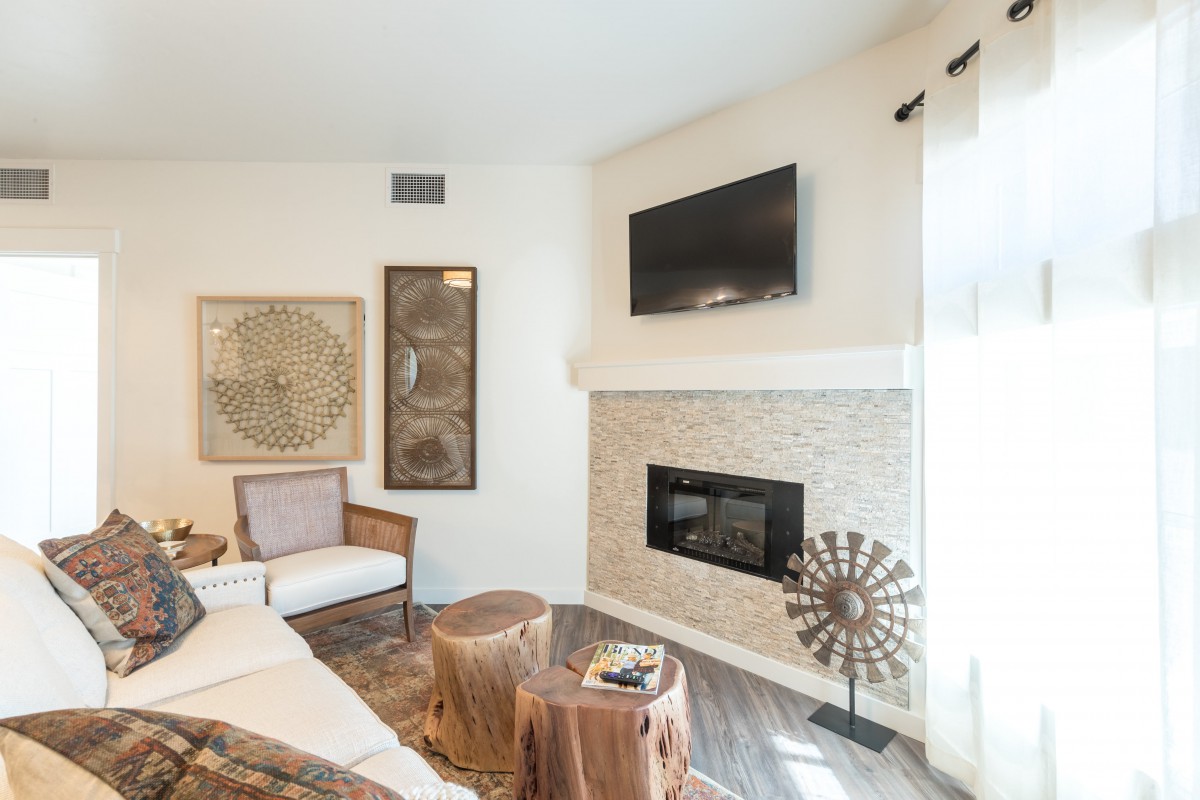 A modern living room with a fireplace, wall-mounted TV, and stylish artwork.
