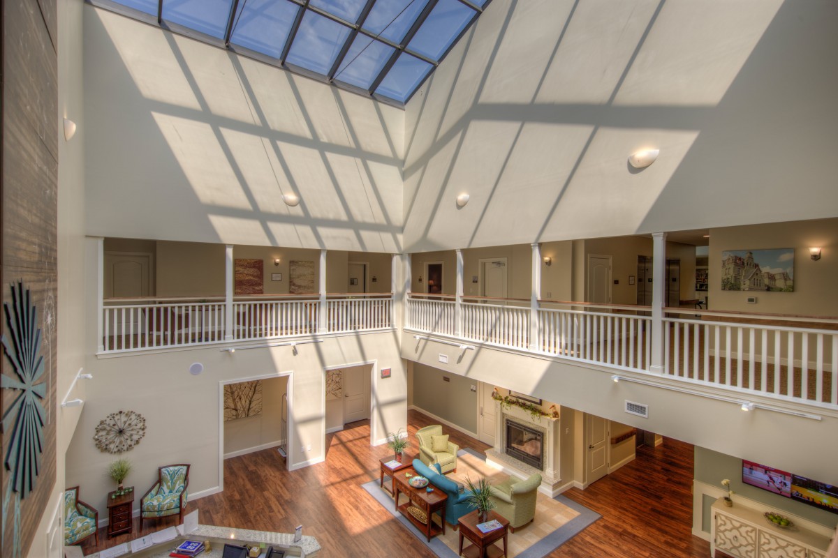 A spacious atrium with a skylight, featuring balconies and a comfortable seating area below.