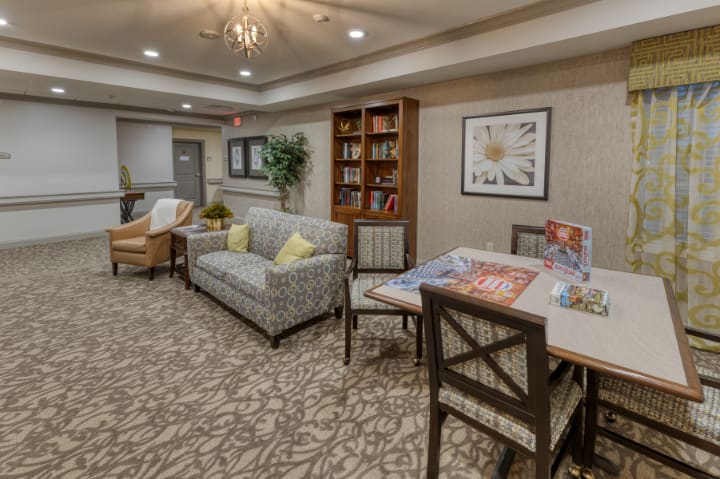 A cozy living room with a sofa, chairs, bookshelf, and a table in a well-decorated space.