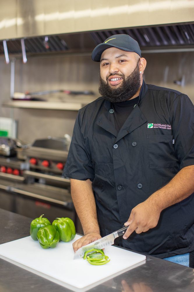 A chef in a kitchen preparing green peppers.