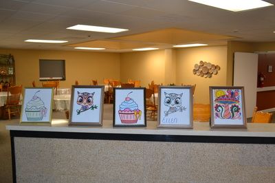 Framed cupcake and animal drawings displayed in an interior space.