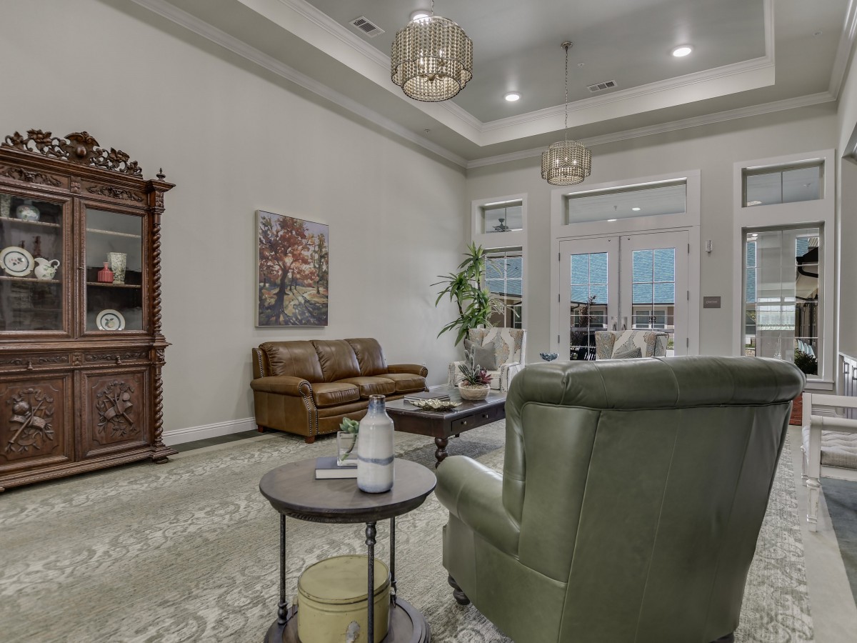 A cozy living room with elegant furniture and tasteful decor, featuring a sofa, armchair, coffee table, and wall art.
