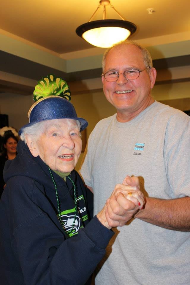 Elderly woman and man dancing and smiling together at a celebration.