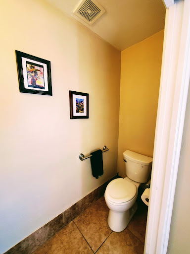 A small, neatly arranged bathroom featuring a toilet and decorative wall art.