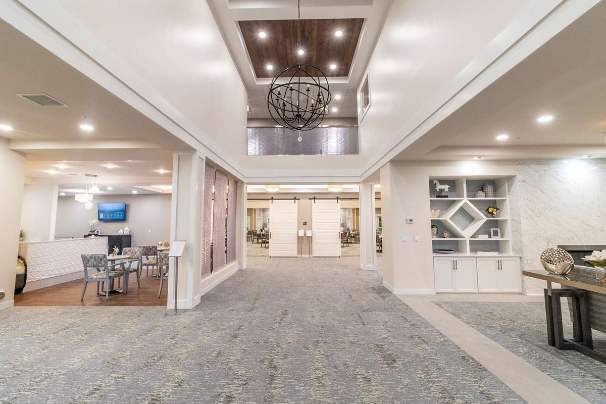 A spacious and modern lobby featuring bright lighting and a decorative chandelier.