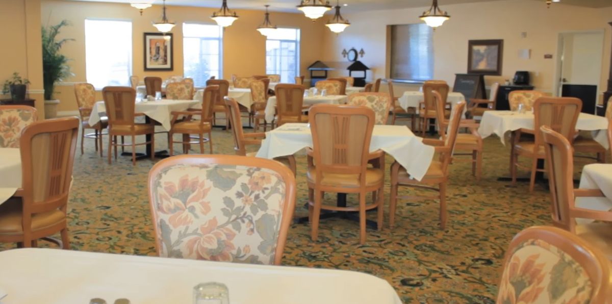 A well-lit dining room with neatly arranged tables and chairs.