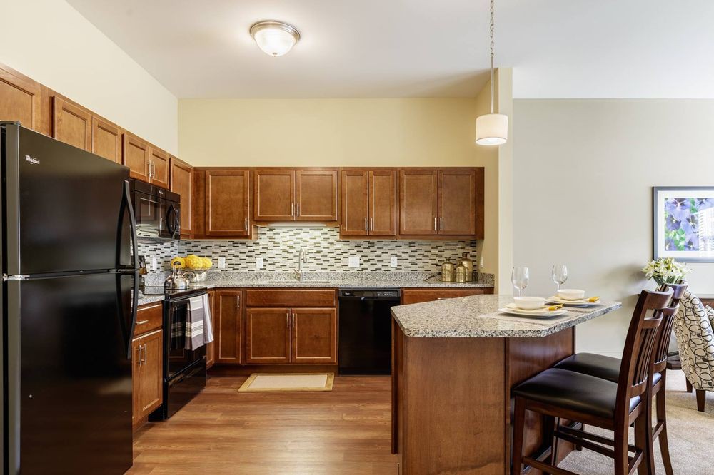 A modern kitchen with wooden cabinets, black appliances, and a tiled backsplash.