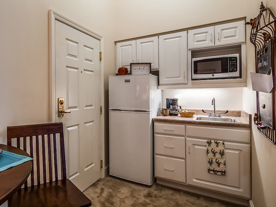 A small kitchen area with a refrigerator, microwave, and sink.