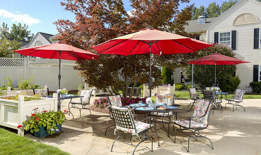 A sunny patio with red umbrellas and outdoor seating.