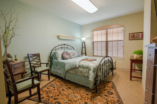 A cozy and well-lit bedroom featuring a decorative bed, comfortable chairs, and a warm color palette.