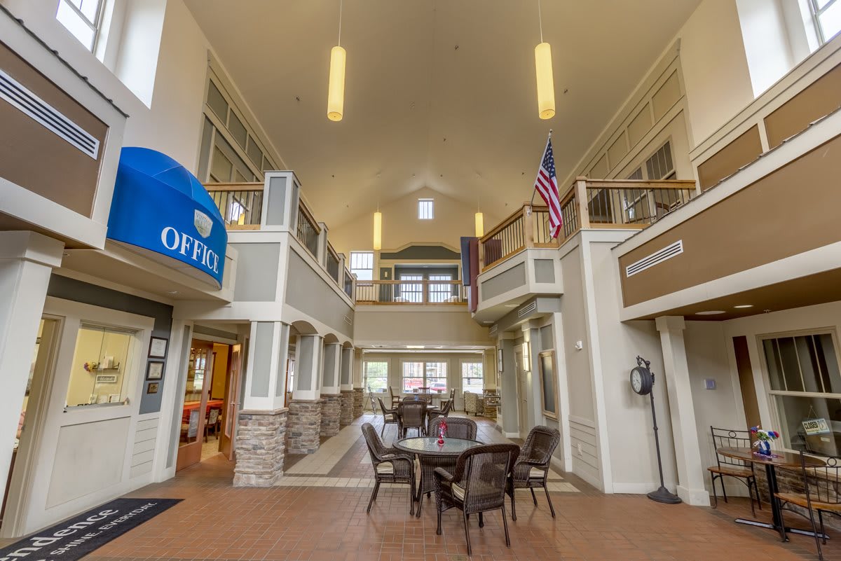 A spacious lobby interior with an office sign, table and chairs, and an American flag.