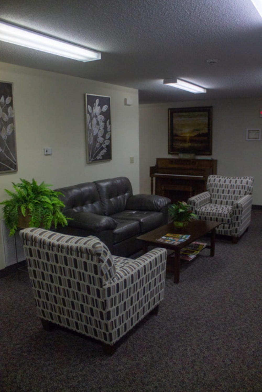 A cozy living room with a couch, armchairs, and a piano.