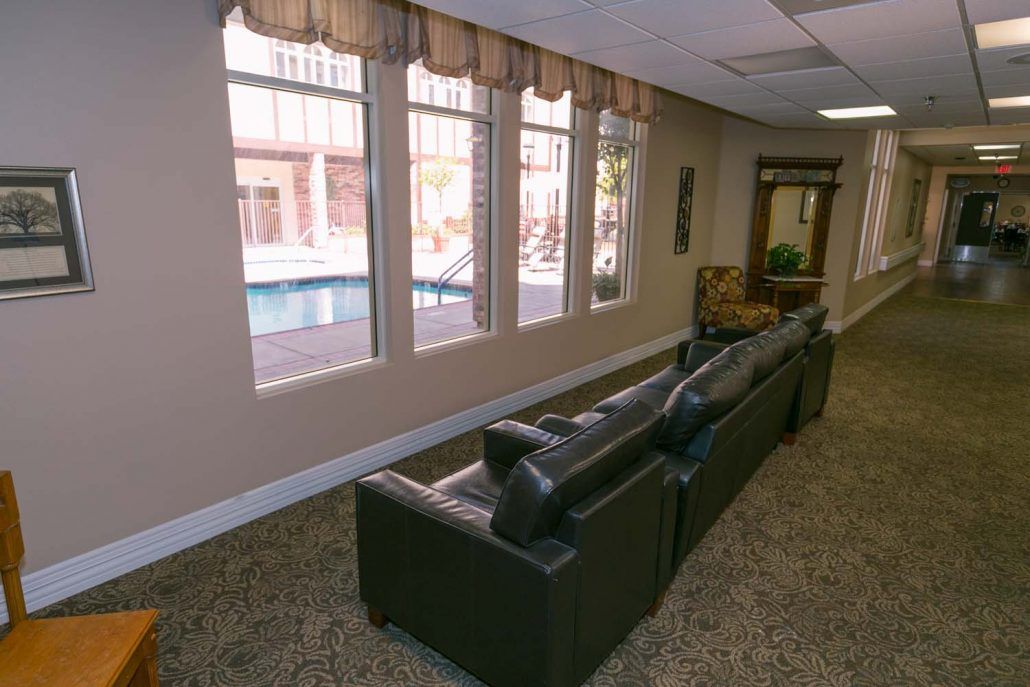 A cozy lobby area with comfortable couches and large windows offering a view of the pool outside.