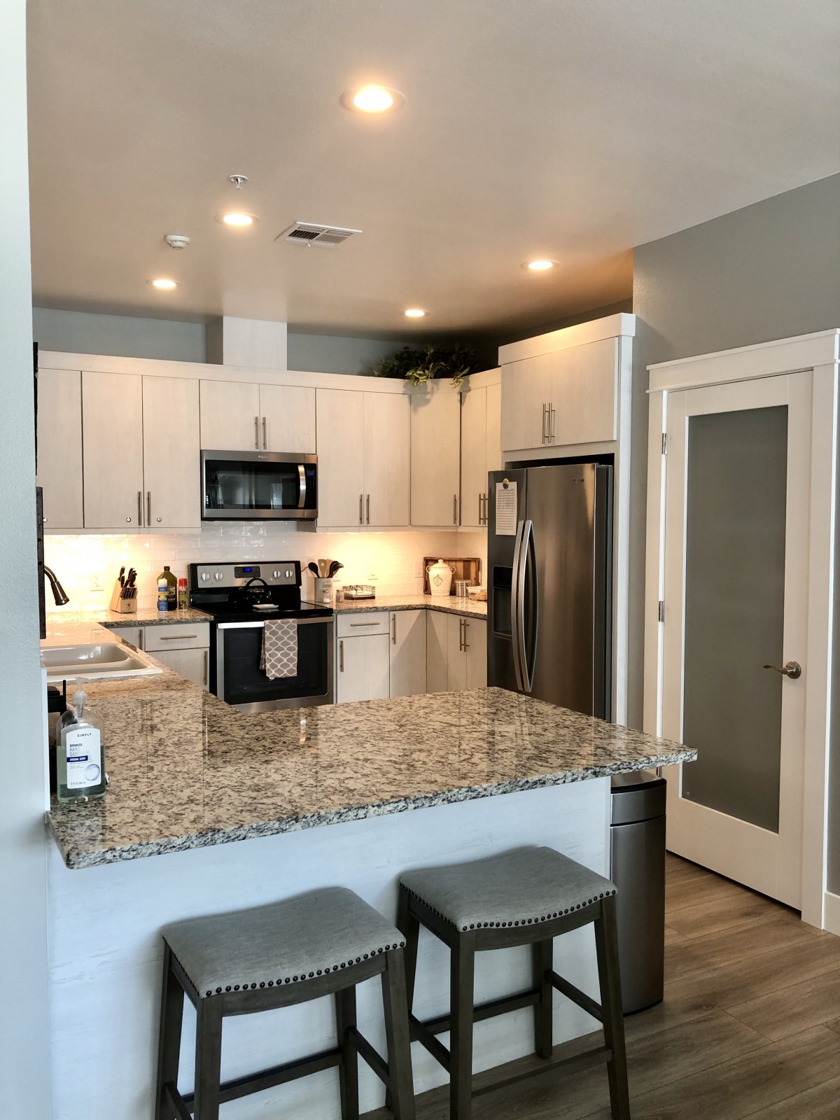 A modern kitchen with white cabinets, granite countertops, and stainless steel appliances.