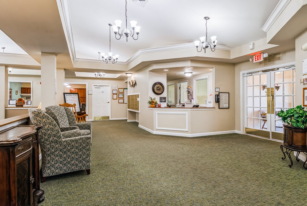 A spacious lobby with a reception desk, comfortable seating, and elegant chandeliers.