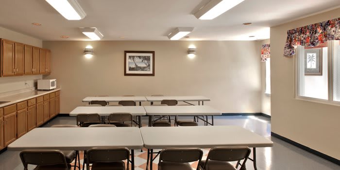 An empty classroom or meeting room with rows of tables and chairs.
