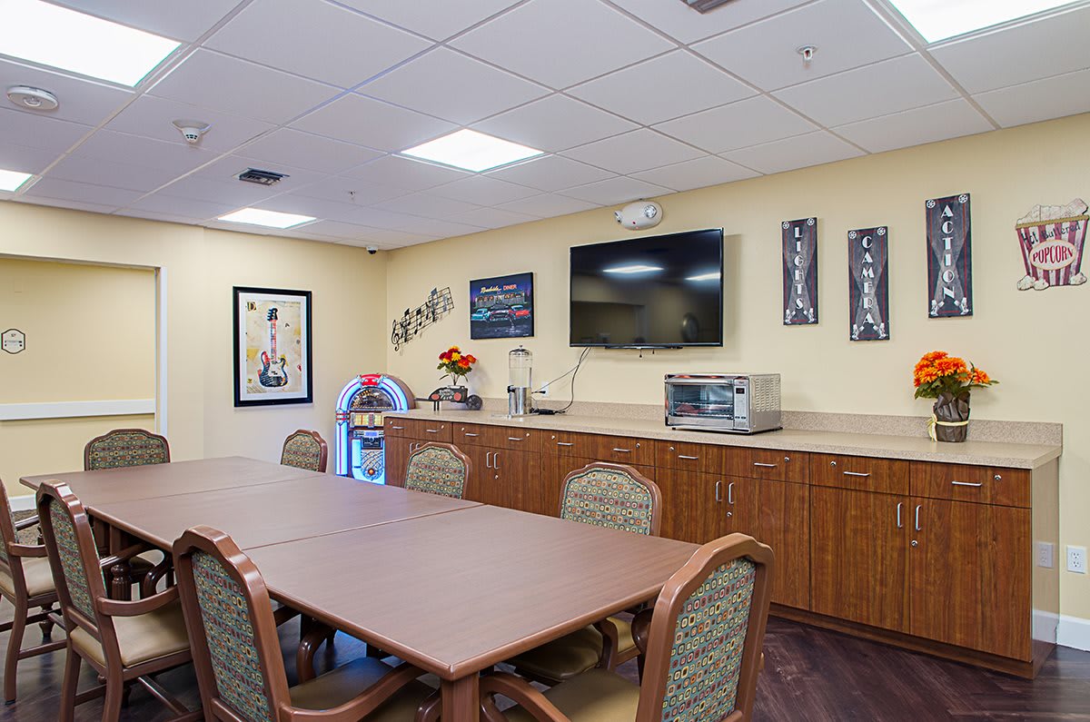 A conference room setup with a long table, chairs, and amenities such as a television and microwave.