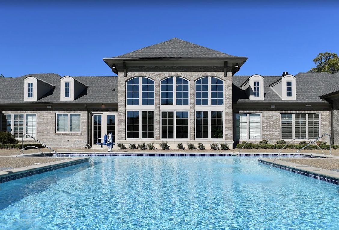A luxurious house with a large swimming pool in front.
