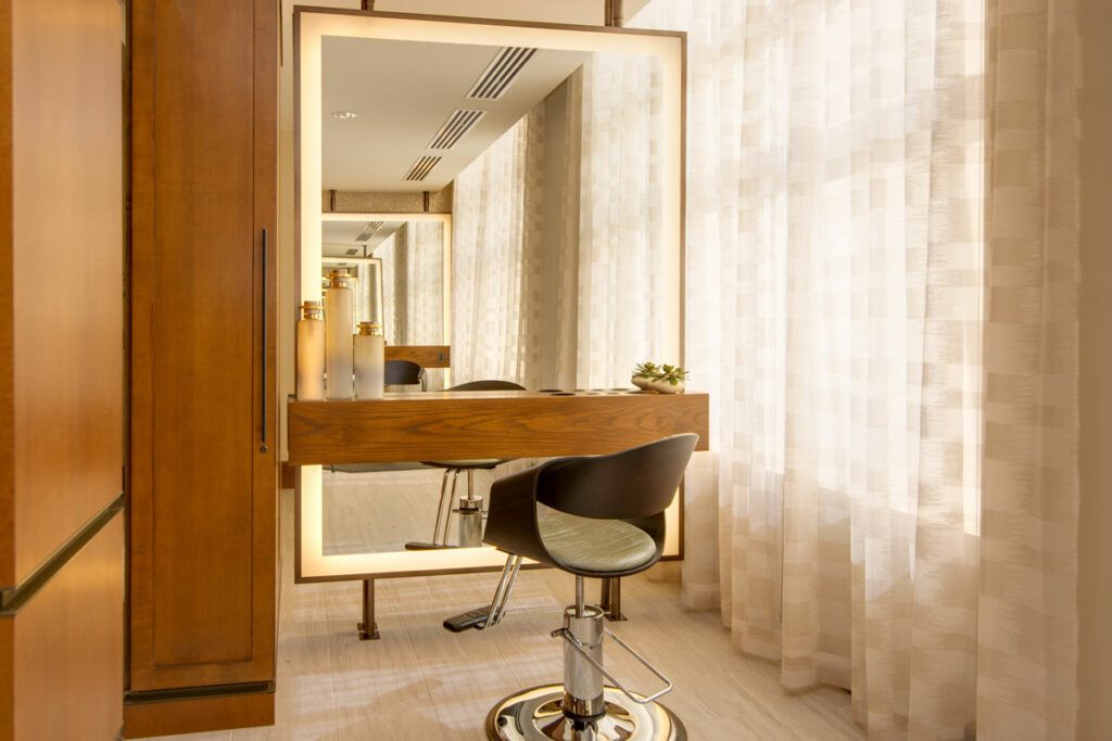 A modern salon setup featuring a large illuminated mirror and a comfortable styling chair.