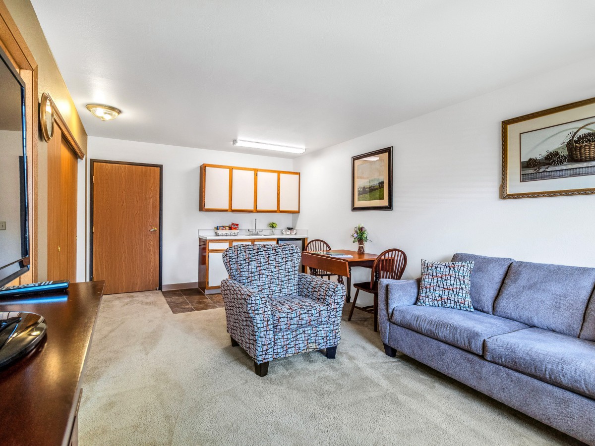 A cozy living room with a sofa, armchair, and a small dining table set.